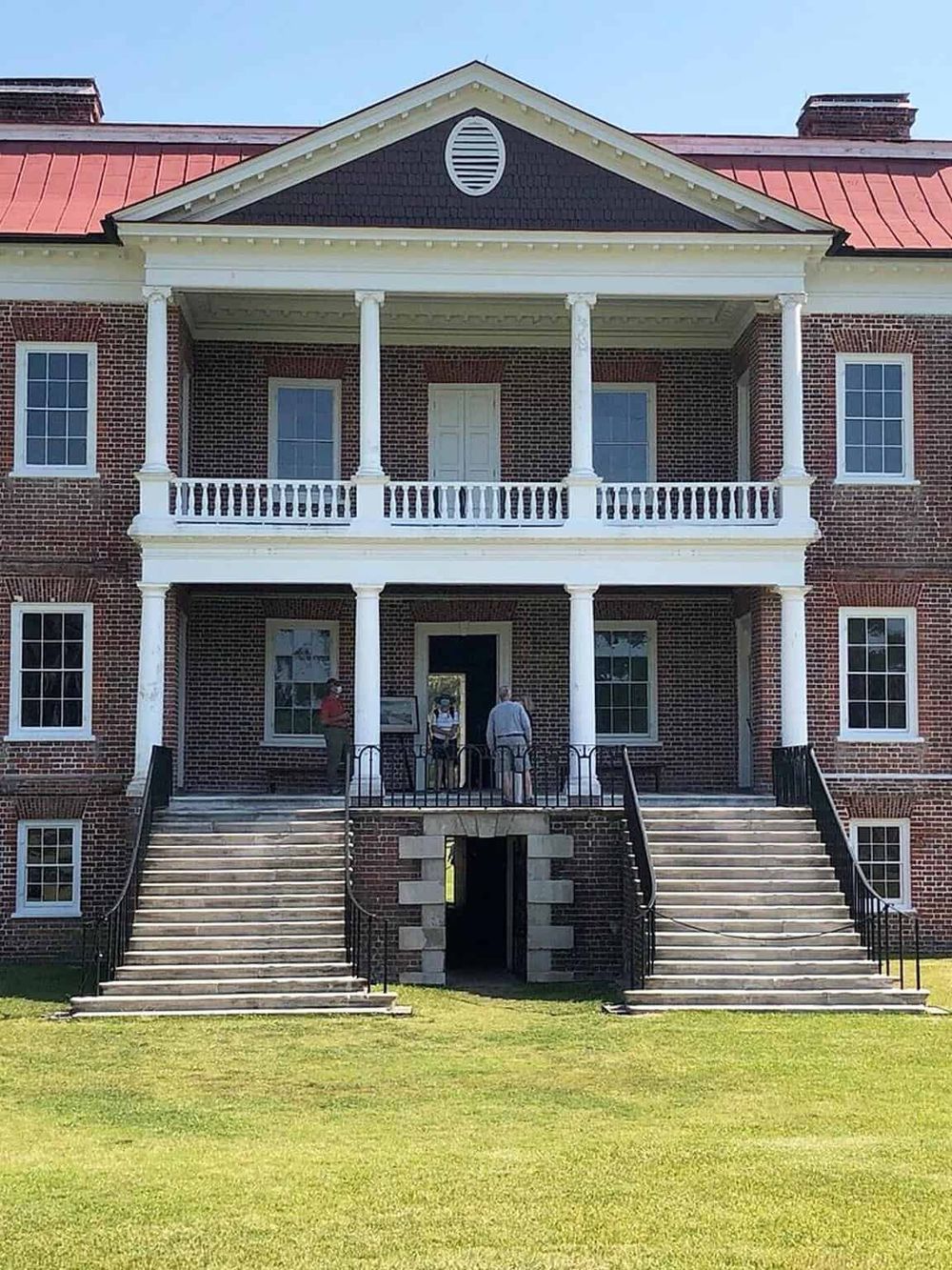 Historic brick mansion with a grand staircase and pillars, showcasing classic American architecture for estate tours.