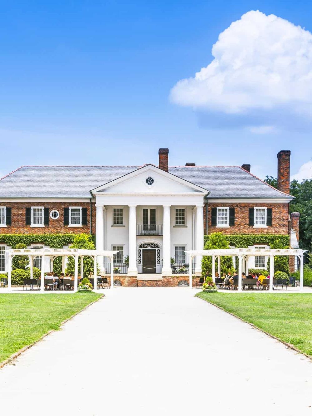 Elegant historic mansion with outdoor seating area and lush green lawn, perfect for events and gatherings.