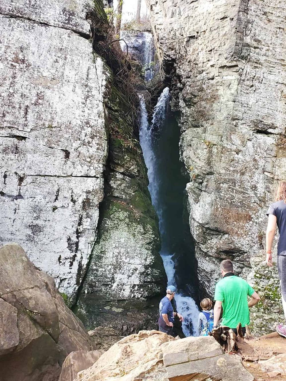 Hidden waterfall in a rugged canyon with visitors exploring scenic trails.