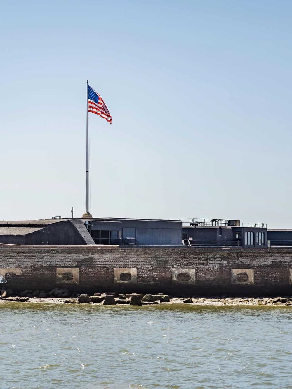 American flag on historic fort overlooking water, symbolizing U.S. landmarks and navigation guidance.