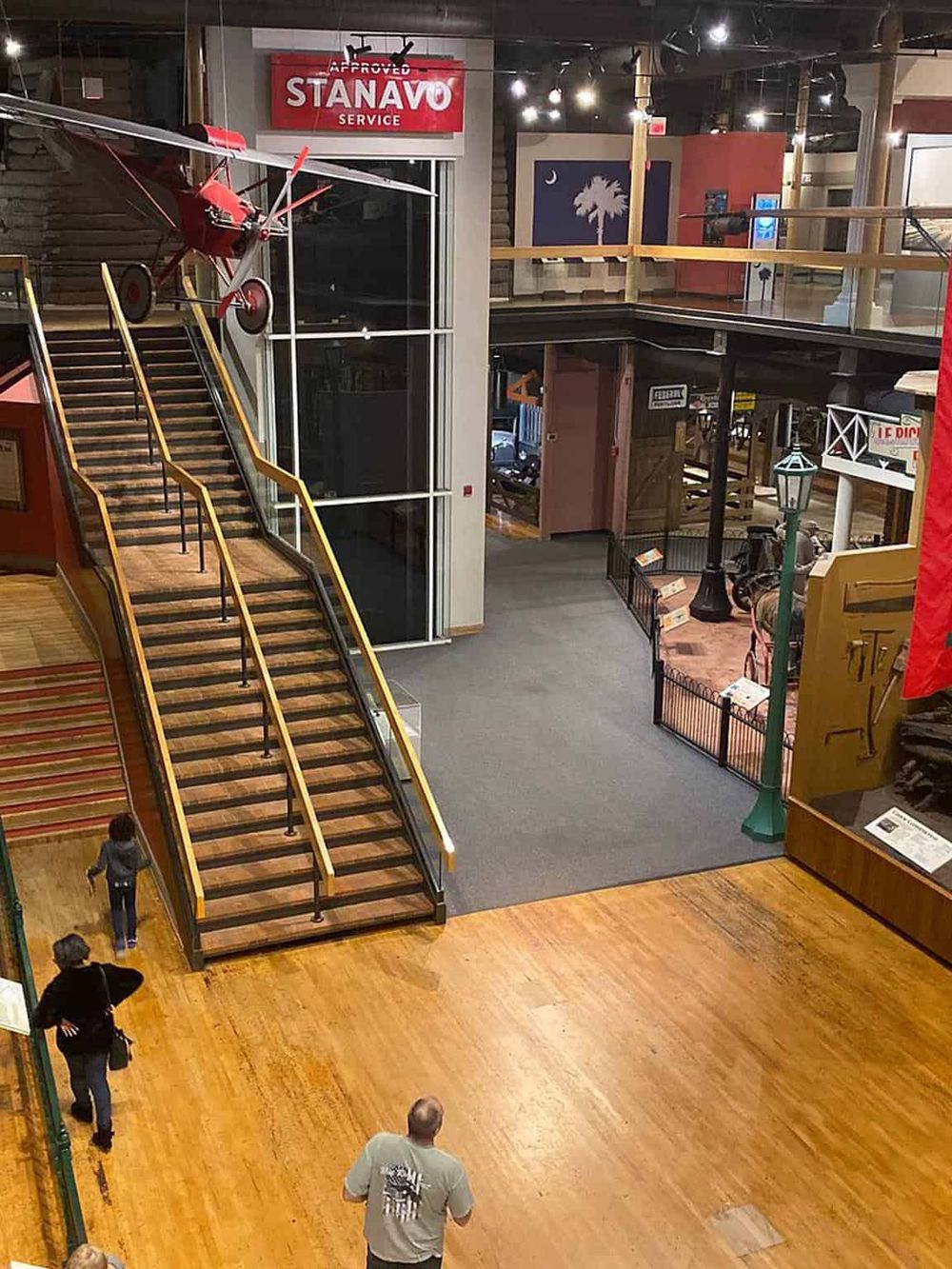 Bright indoor shopping mall with wooden flooring, colorful signs, and vintage decor elements.