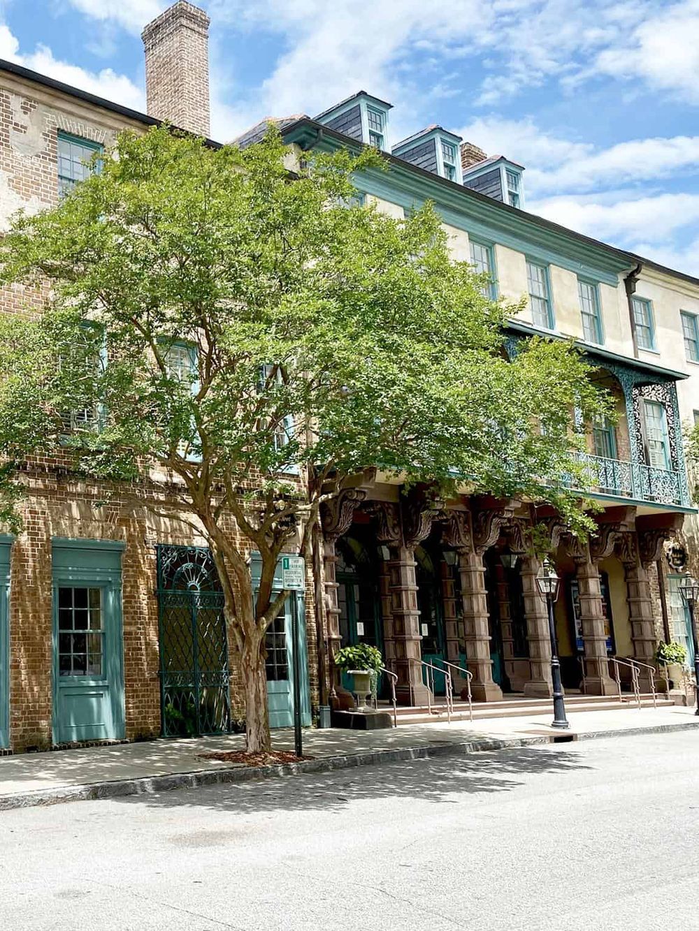 Historic building with classic architecture, green door, and a tree on a city street.