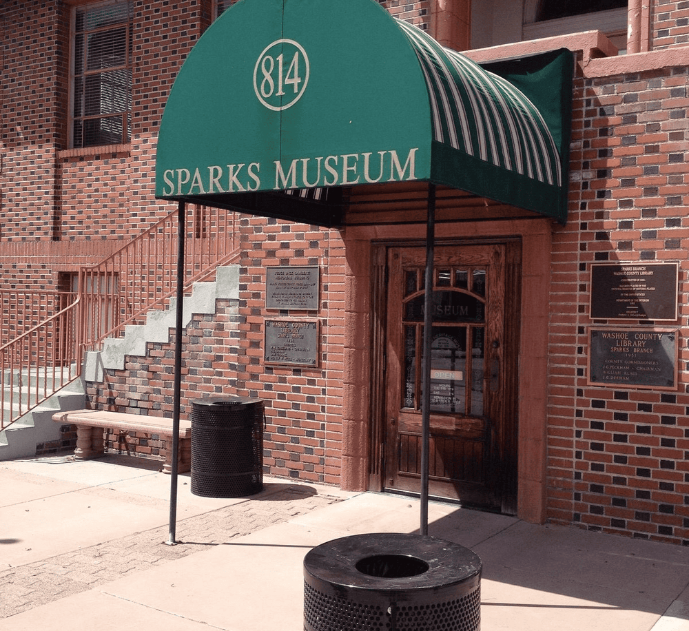 Outdoor entrance of Sparks Museum with green awning, brick building, and street signage.