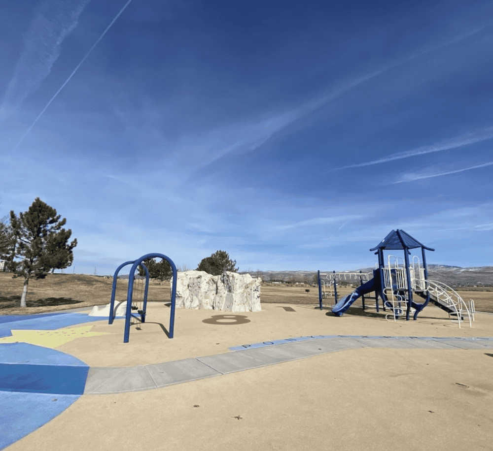 Sunny outdoor playground with slides and swings at QuestForDirections park in a spacious, open landscape.