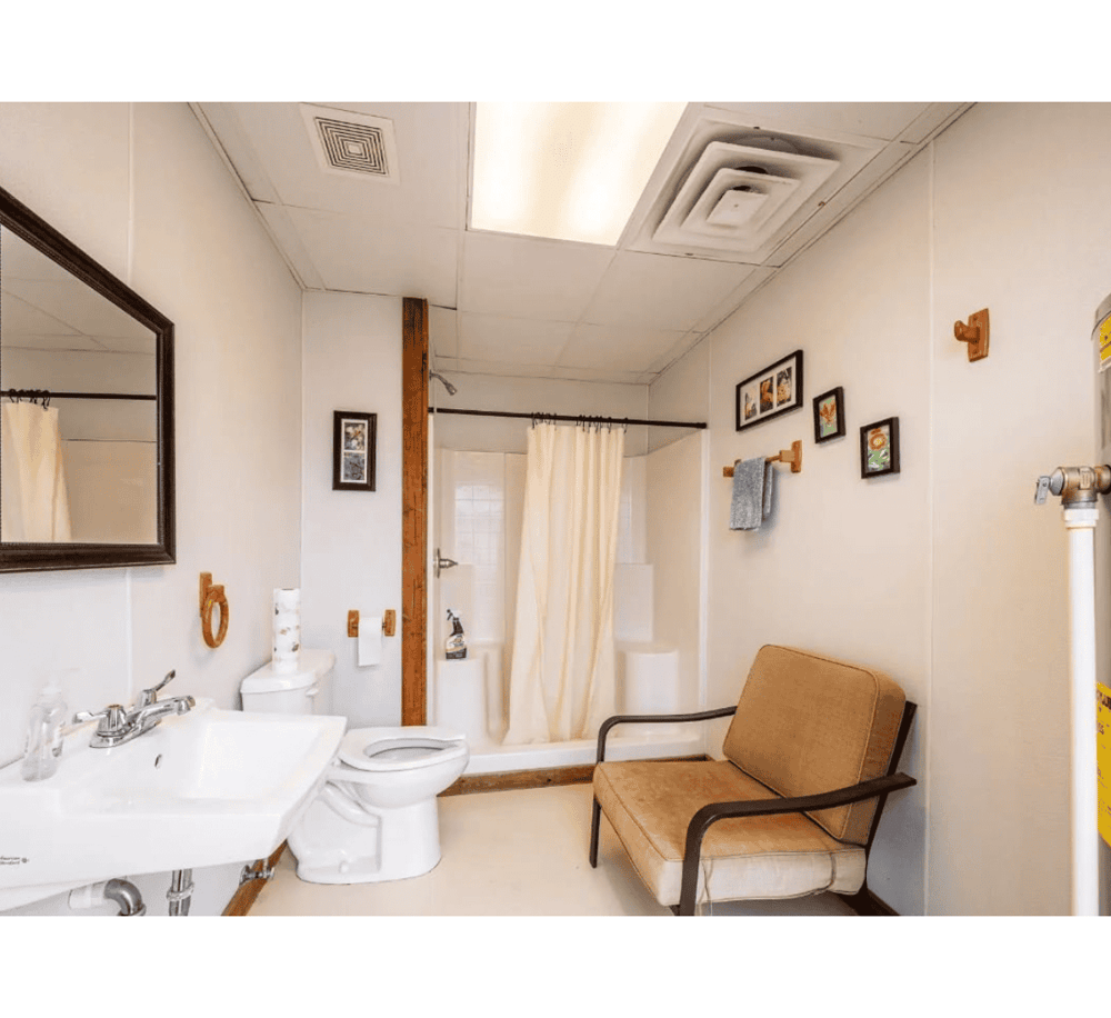 Clean accessible bathroom with shower, toilet, sink, and grab bars at Quest For Directions.