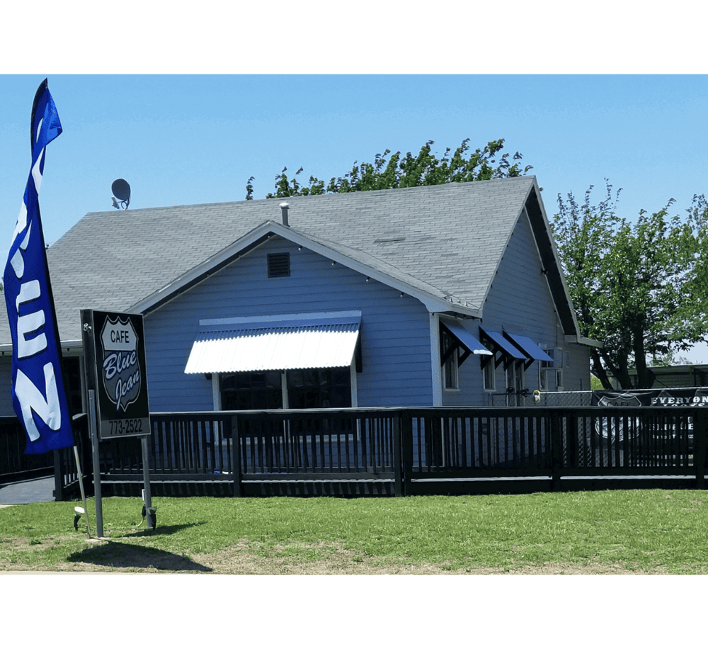Blue Ocean Cafe exterior with signage, outdoor seating area, and flag, in a scenic setting.