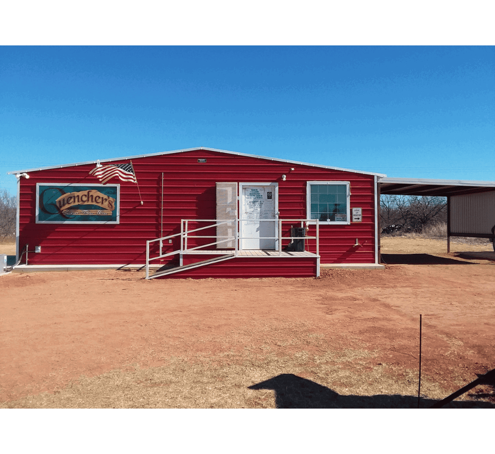 Quencher's outdoor building with red siding, American flag, and directional signage for local attractions.