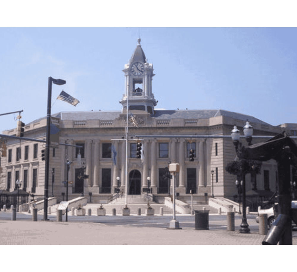 Historic city hall building with clock tower and American flags.