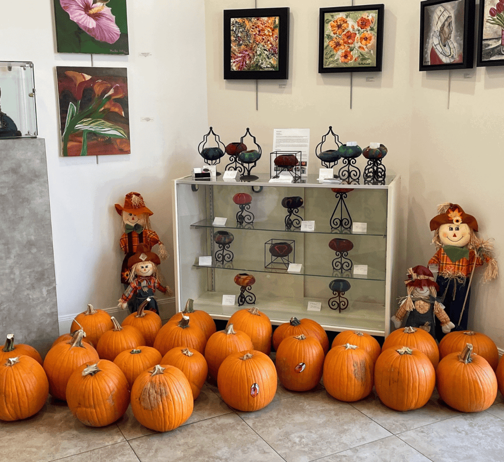 Pumpkin display with fall-themed decorations and artwork, showcasing seasonal home decor ideas.