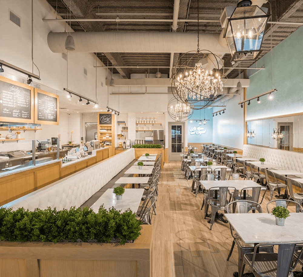 Bright modern cafe interior with elegant chandeliers, cozy seating, and a welcoming atmosphere.