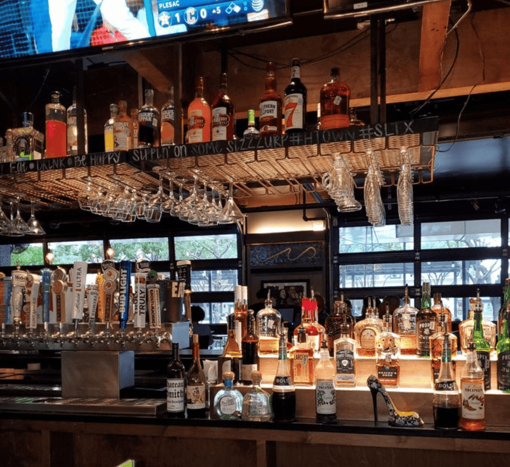 Relaxing bar with an array of liquor bottles and hanging glassware at QuestForDirections.