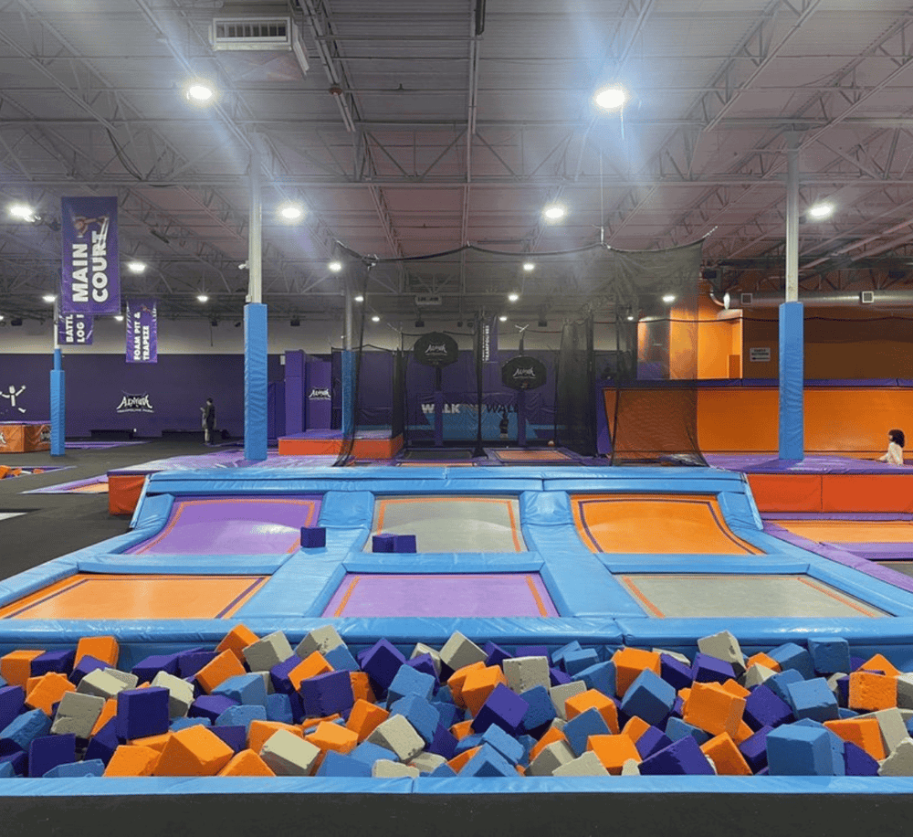 Colorful trampoline park with foam pits and wall obstacles for kids and teens.