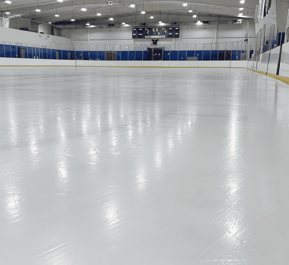 Shiny indoor ice rink with smooth surface and clear reflective ice, perfect for hockey and skating activities.