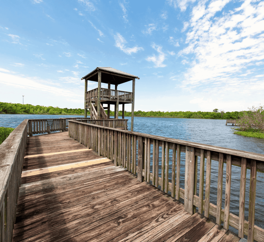 Aerial view of a wooden observation tower over water with a clear blue sky in the background.