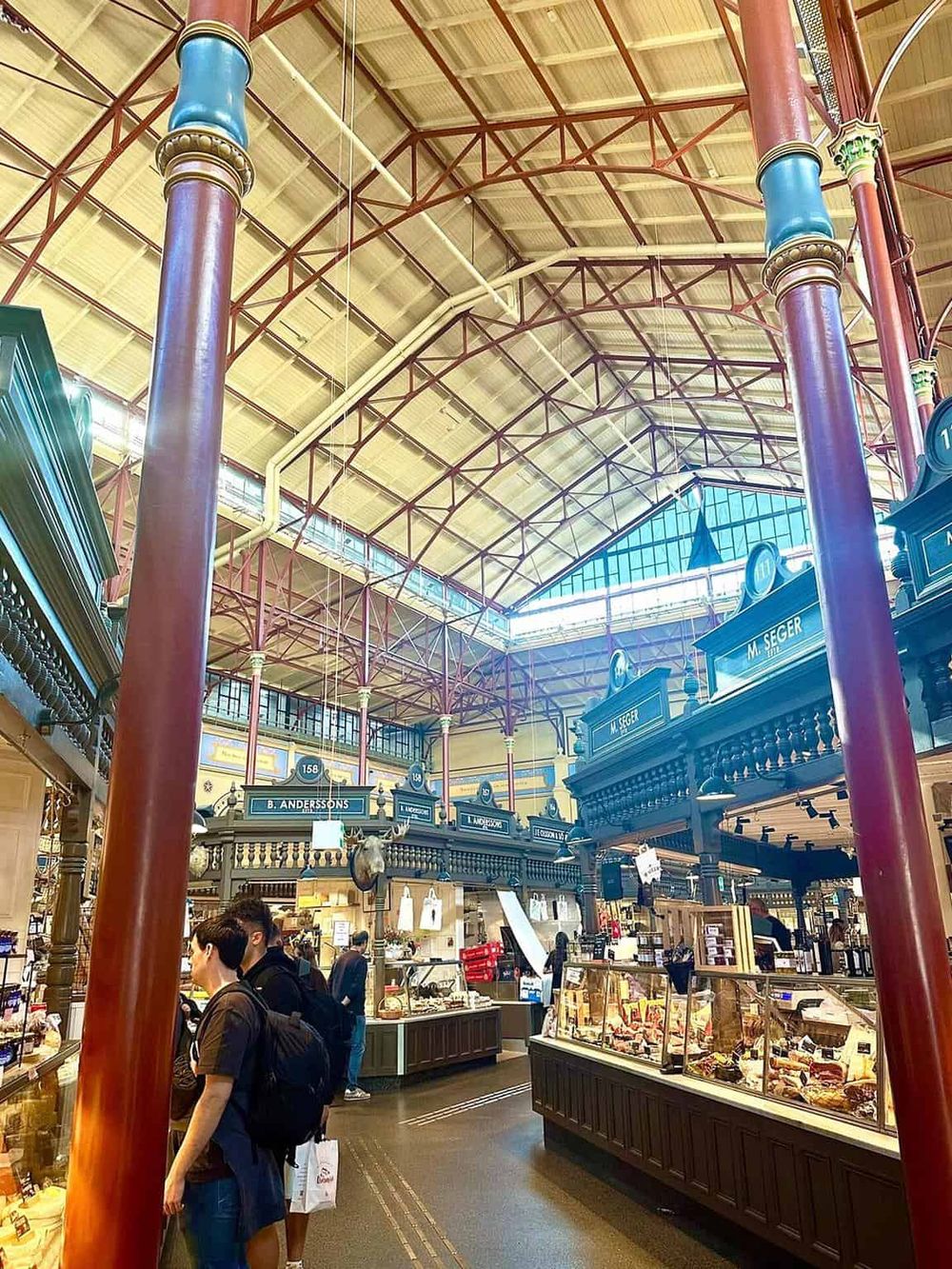 Vibrant indoor marketplace with vintage-style booths and high arched glass ceiling.