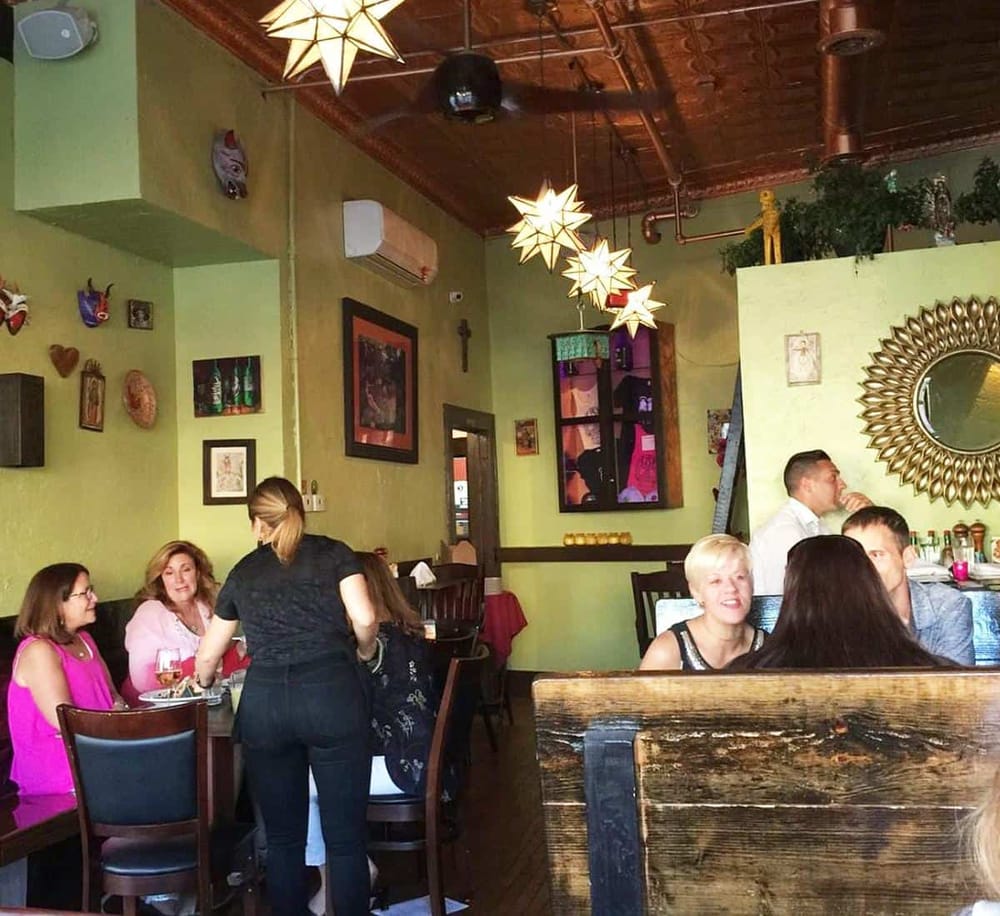 Cozy restaurant interior with vibrant decor, hanging star-shaped lamps, and diverse group dining experience.