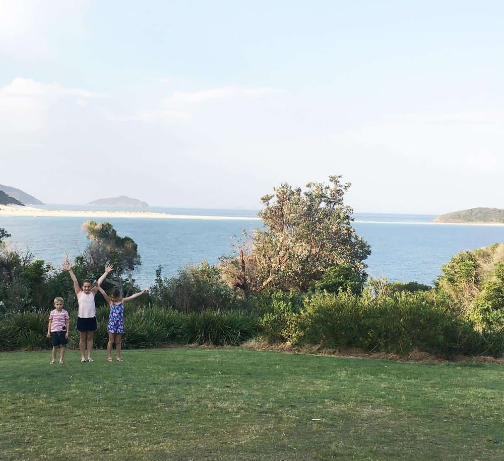 Tranquil coastal landscape with children enjoying nature, lush greenery, and ocean views, perfect for travel and outdoor adventure.