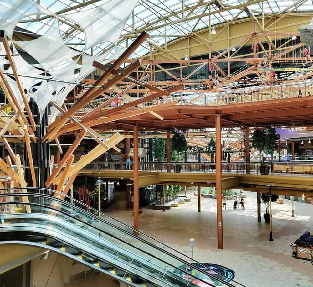 Modern multi-level shopping mall with distinctive wooden and steel architectural design.