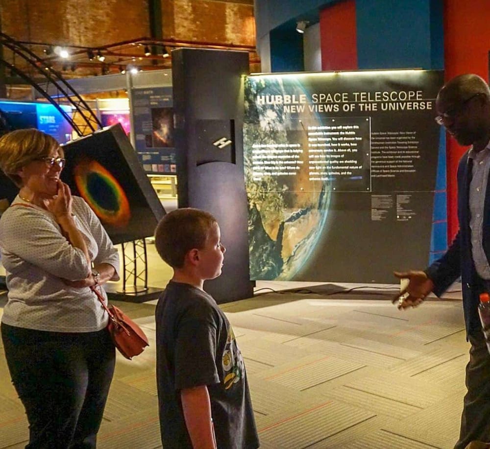 Vivid display at a space museum highlighting the Hubble Space Telescope and universe exploration. Visitors engaged in educational science exhibits.