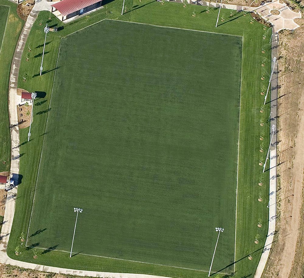 Aerial view of a well-maintained sports field with lighting, ideal for community recreation and sports activities.