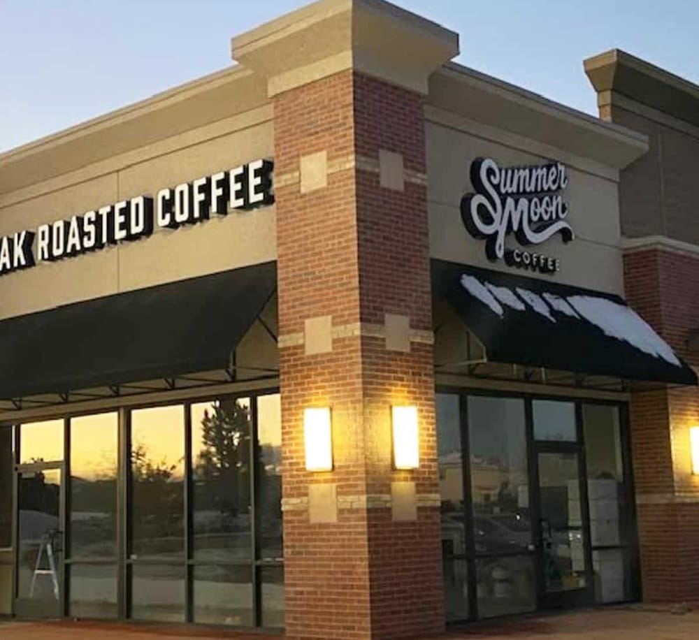 Cozy coffee shop exterior with brick accents, featuring "Oak Roasted Coffee" and "Summer Moon Coffee" signage.