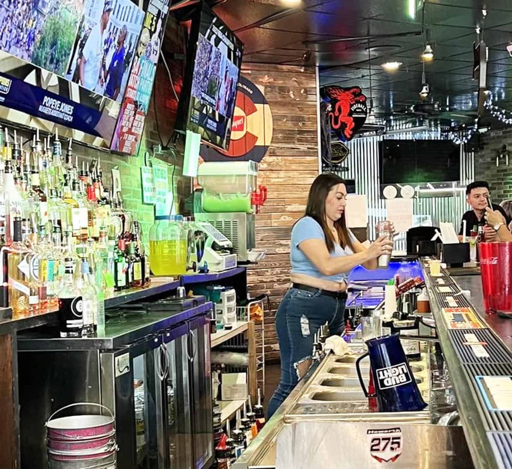 1. Bar with liquor bottles, TVs, and bartenders in a lively sports bar setting.