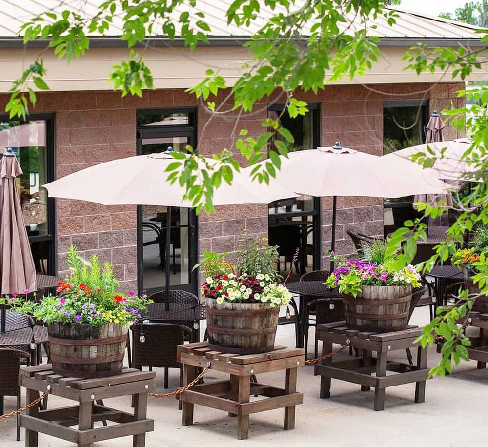 Elegant outdoor patio with flowers, umbrellas, and seating, perfect for dining and relaxation at Quest For Directions.