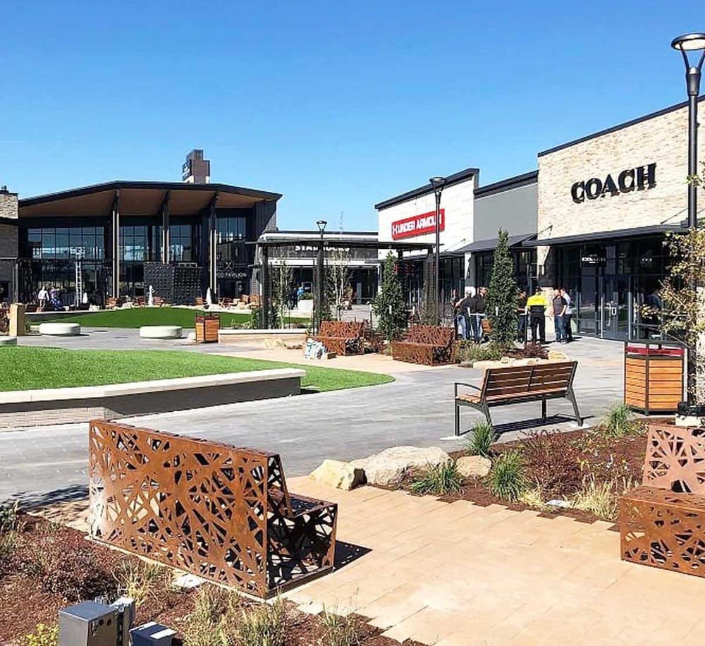 Modern shopping plaza with retail stores and outdoor seating area.