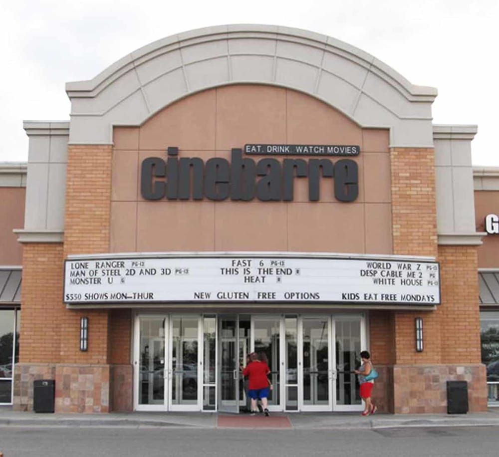 Movie theater entrance with marquee advertising films, located in an urban area.