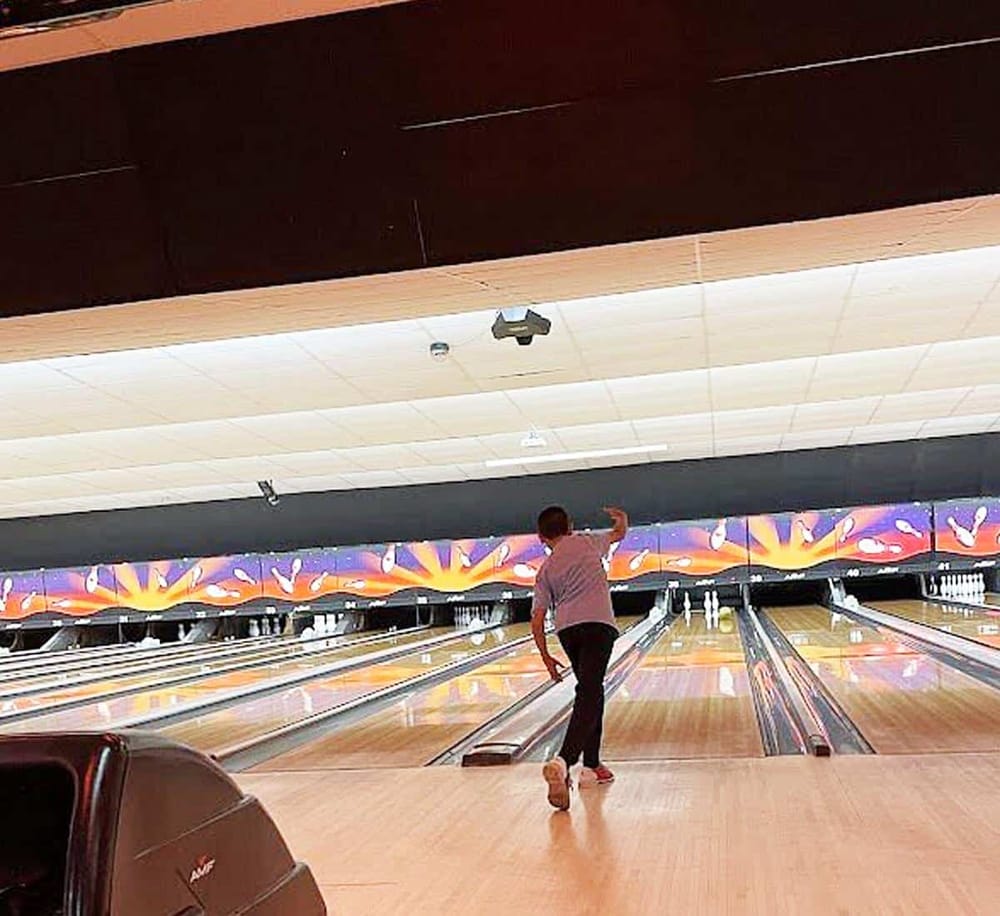 1. Bowling alley with a person throwing a bowling ball for a strike.