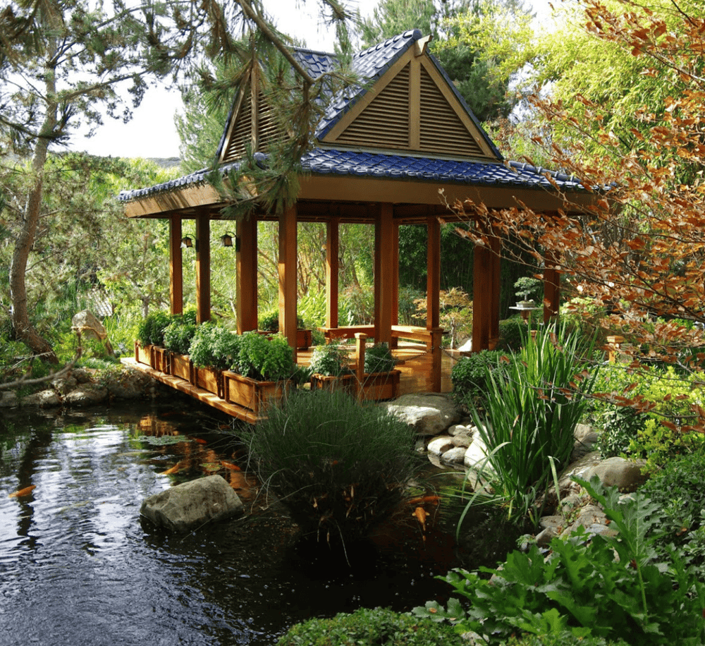 Serene garden gazebo with pond, lush greenery, and wooden accents, perfect for outdoor relaxation.