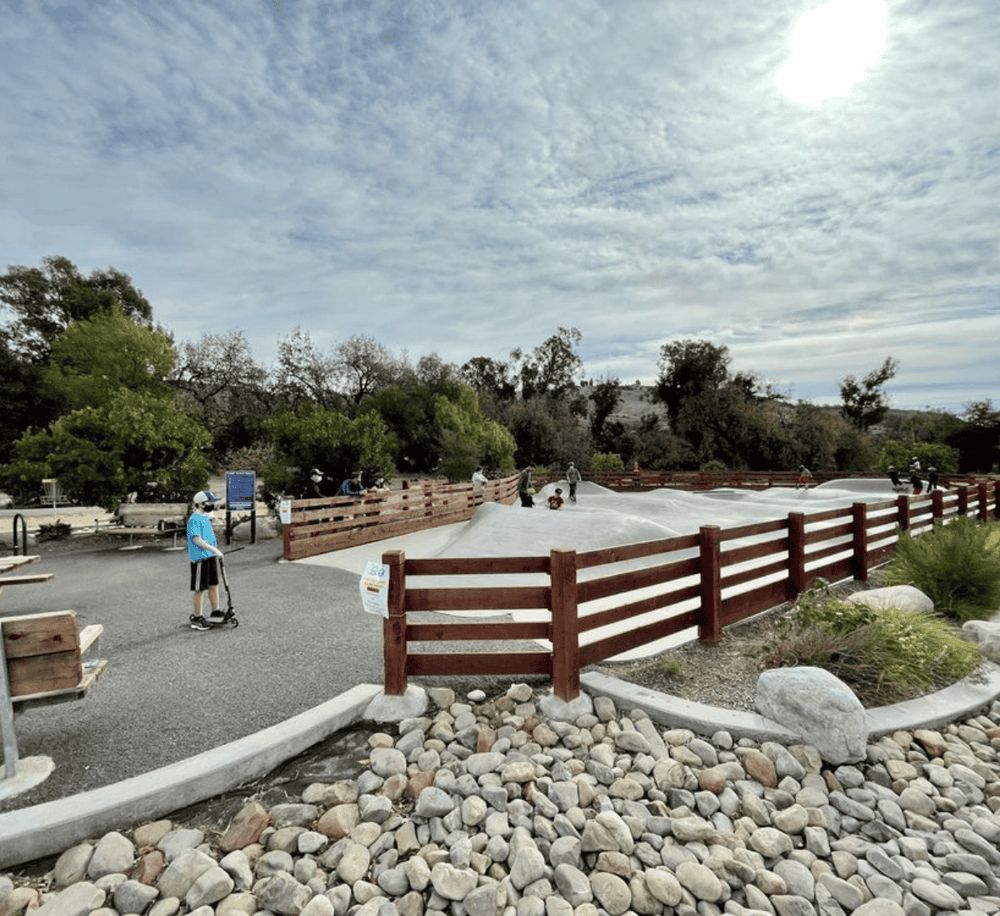 Scooter rider at Quest for Directions outdoor park with climbing structure and scenic nature background.