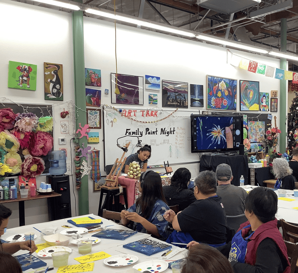 Creative family paint night event with instructor and colorful artwork display, perfect for team building and artistic fun.