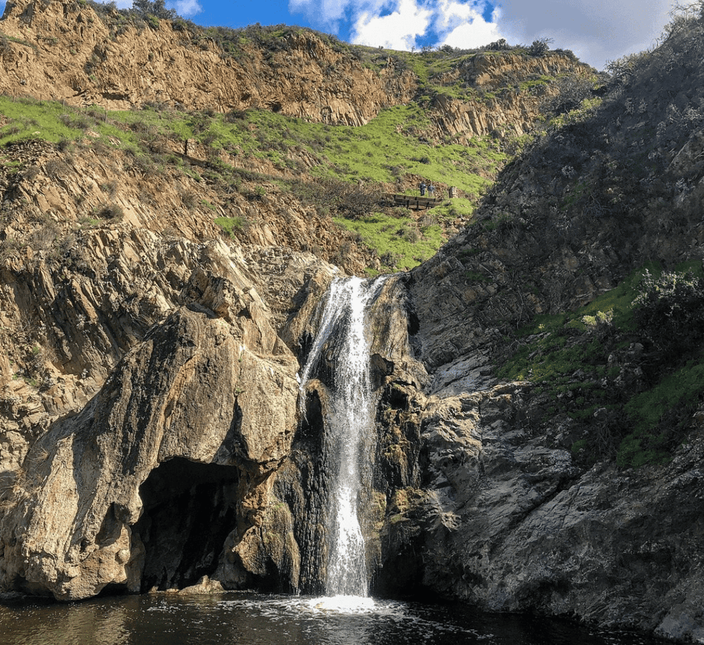Serene mountain waterfall with lush greenery and rocky cliffs, perfect for nature exploration.