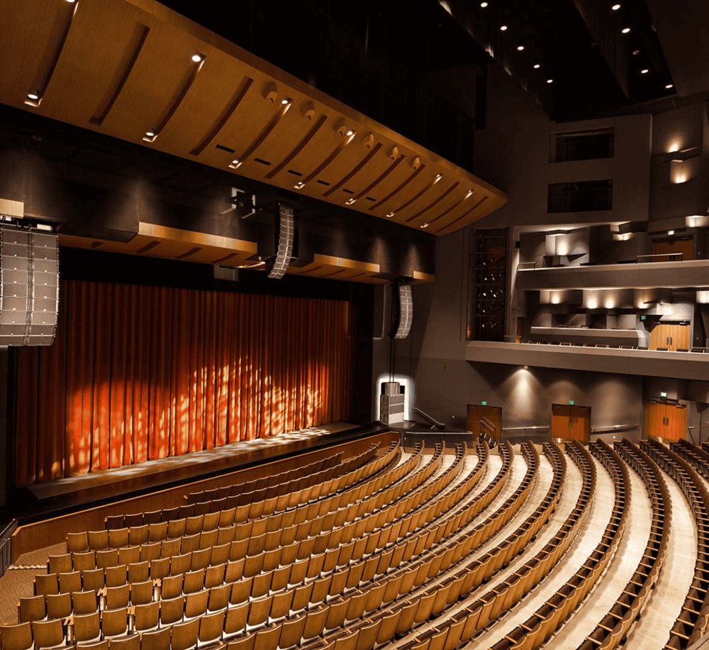 Spacious theater auditorium with stage, seating, and professional audio-visual equipment.