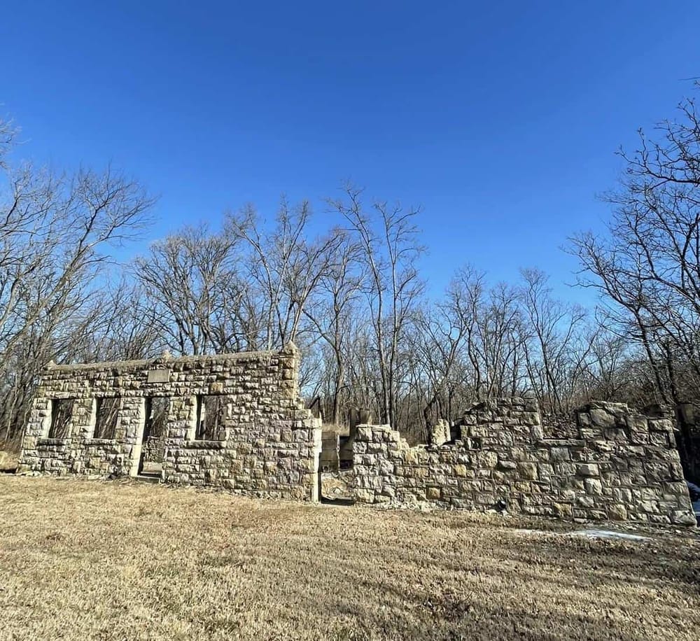 Old stone wall ruins surrounded by leafless trees under a clear blue sky.