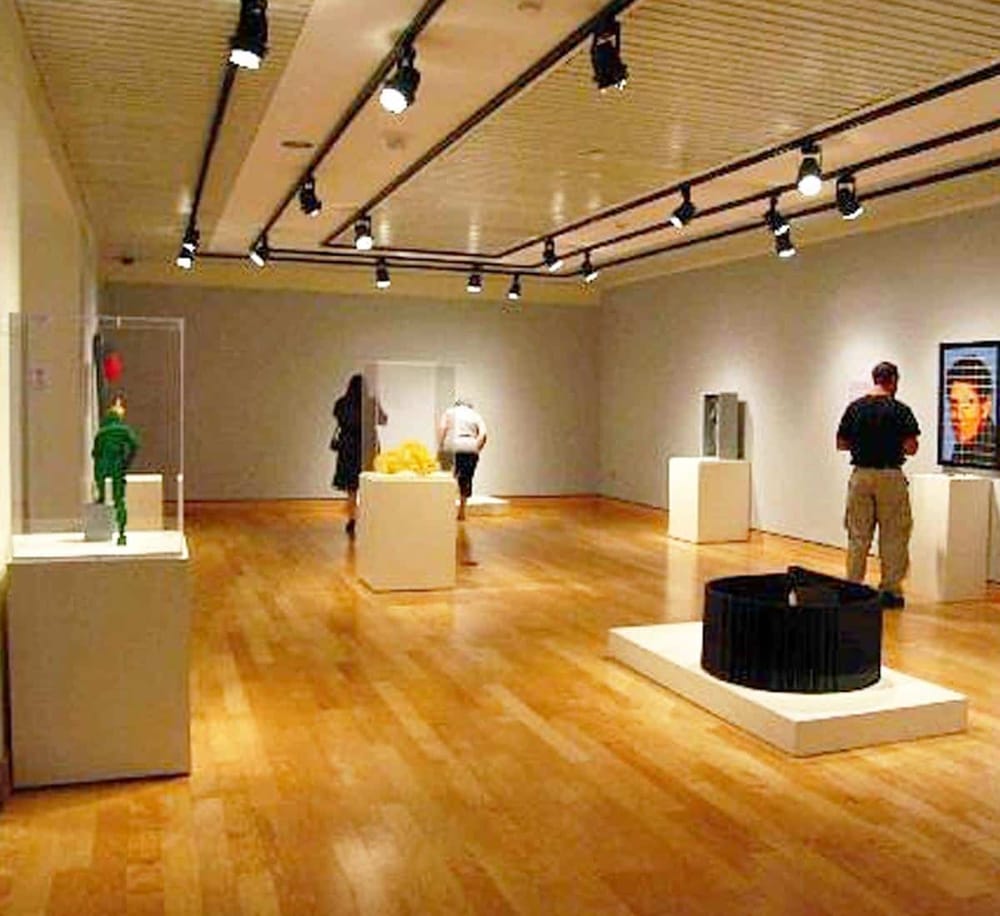 Colorful art gallery with modern sculptures and paintings on display in a spacious, well-lit museum.