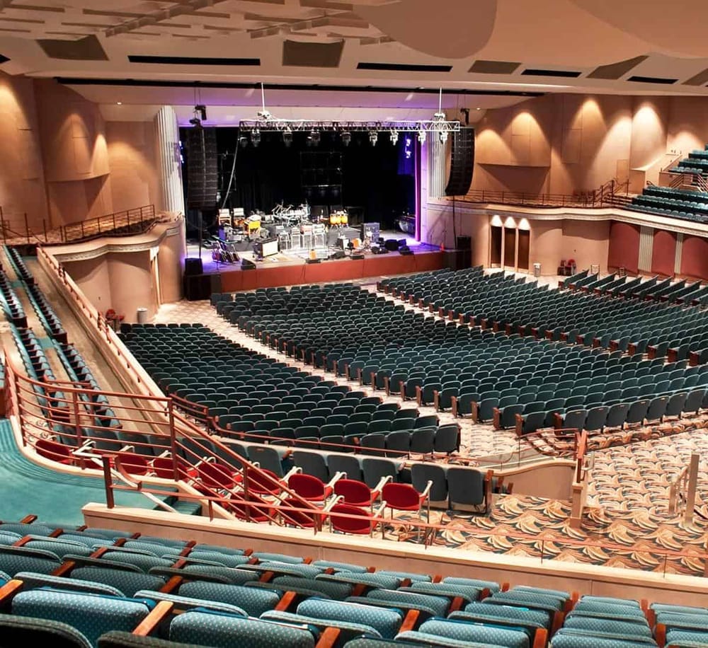 Comfortable theater seating with a stage set for live performances and events.