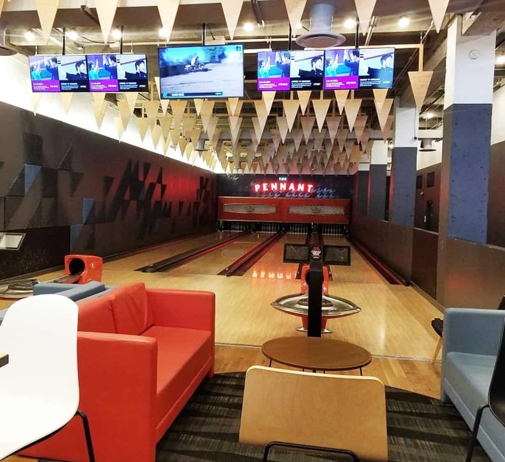 Modern indoor bowling alley with multiple screens and comfortable seating at QuestForDirections.
