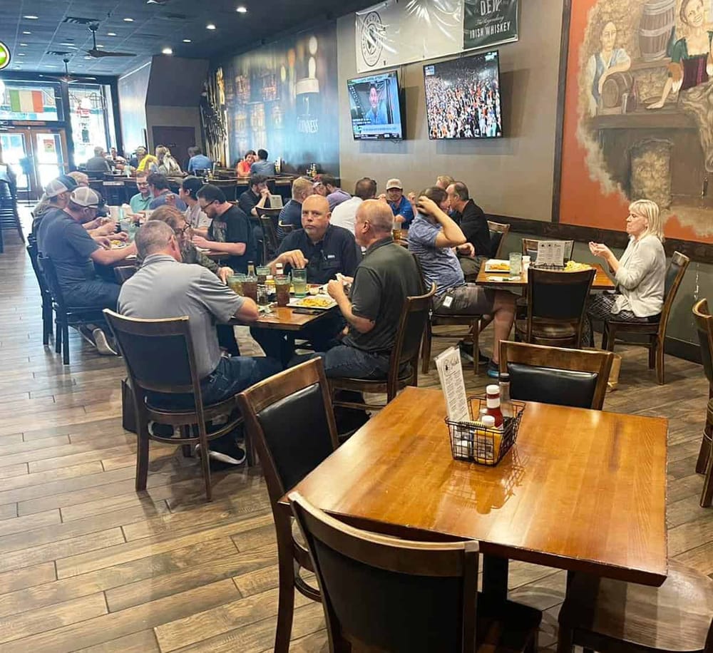 Avenue sports bar interior with patrons enjoying meals and watching games on multiple screens.