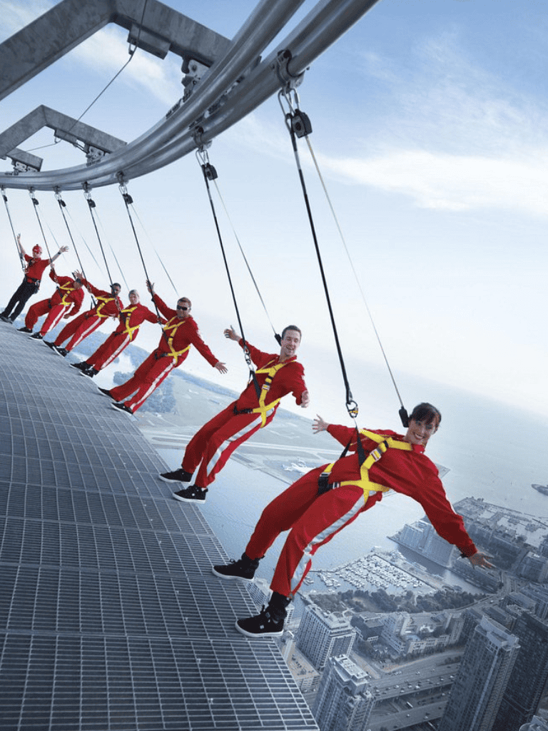 Exciting group of people dressed as Santa on a high-rise swing ride over a city skyline.
