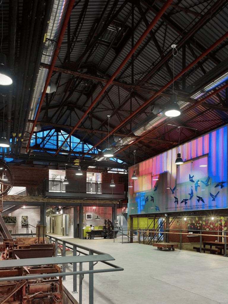 Industrial warehouse interior with colorful LED art display, modern lighting, and open workspace.