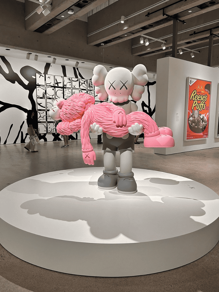 Colorful KAWS-inspired art sculpture with pink and white tones at QuestForDirections exhibit.