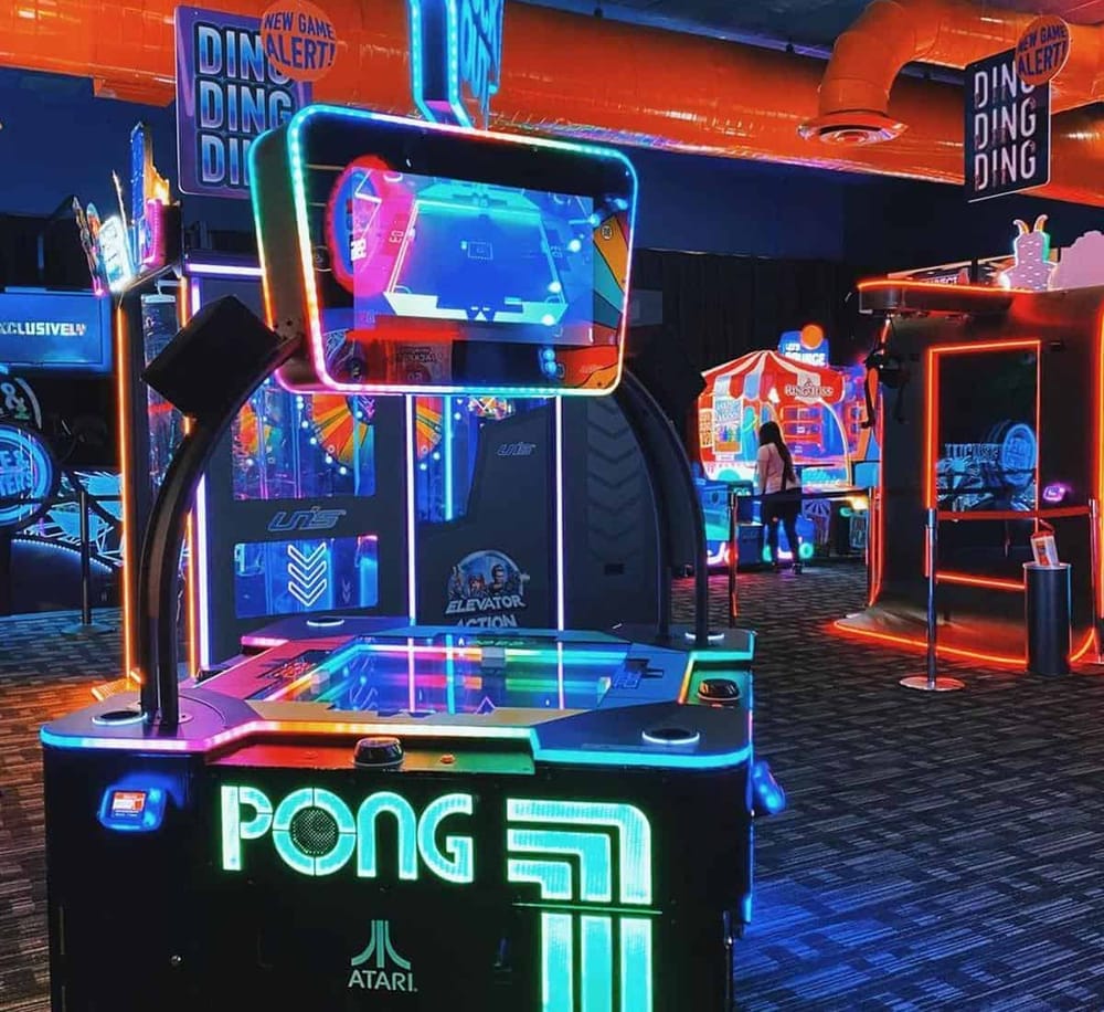 Bright neon-lit arcade with classic and modern games at QuestForDirections entertainment center.