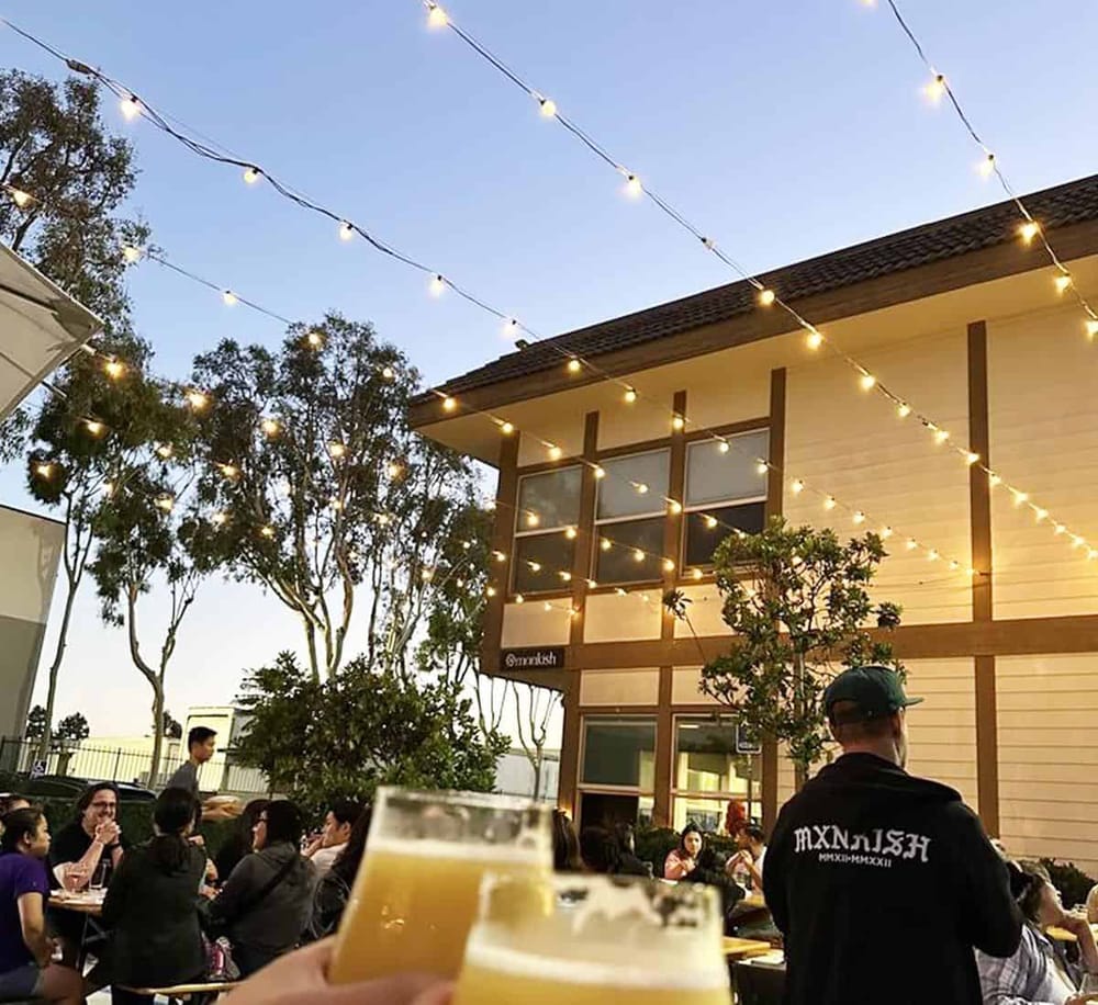 Outdoor dining with string lights at a modern restaurant during sunset.