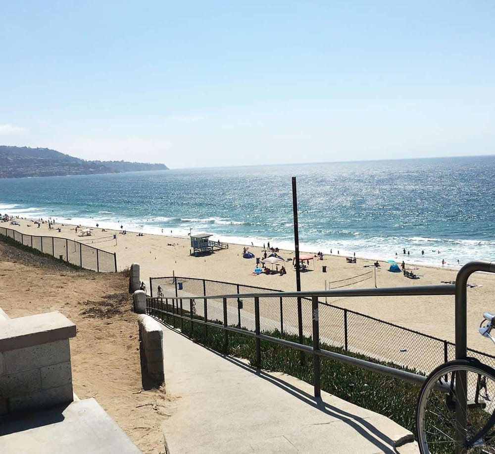 Sunny beach scene with sandy shore, colorful umbrellas, and ocean waves; perfect for travel and vacation planning.