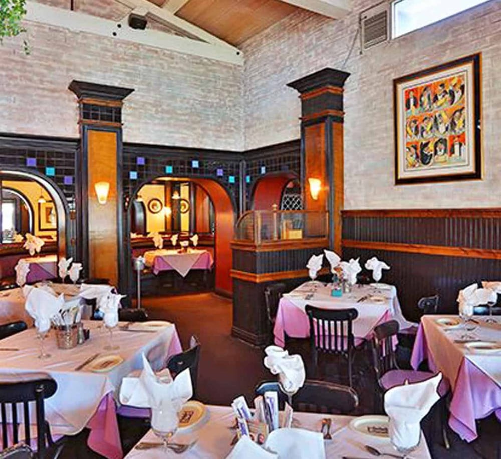Elegant restaurant interior with vibrant decor, pink tablecloths, and artistic wall art, perfect for a fine dining experience.