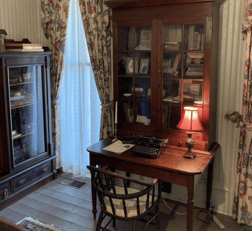 Ornate vintage study room with wooden desk, typewriter, classic lamp, and antique books for historical research.