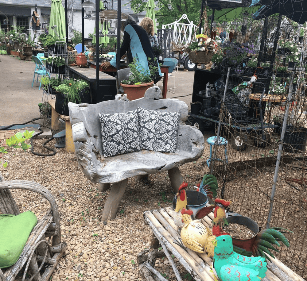 Vintage garden bench with decorative pillows in outdoor plant nursery and garden shop.