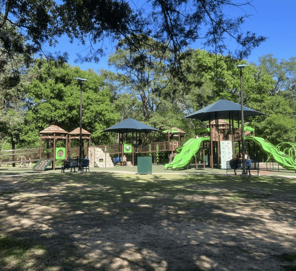 Colorful playground for children in park with slides and shaded structures, ideal for outdoor family fun and recreation.